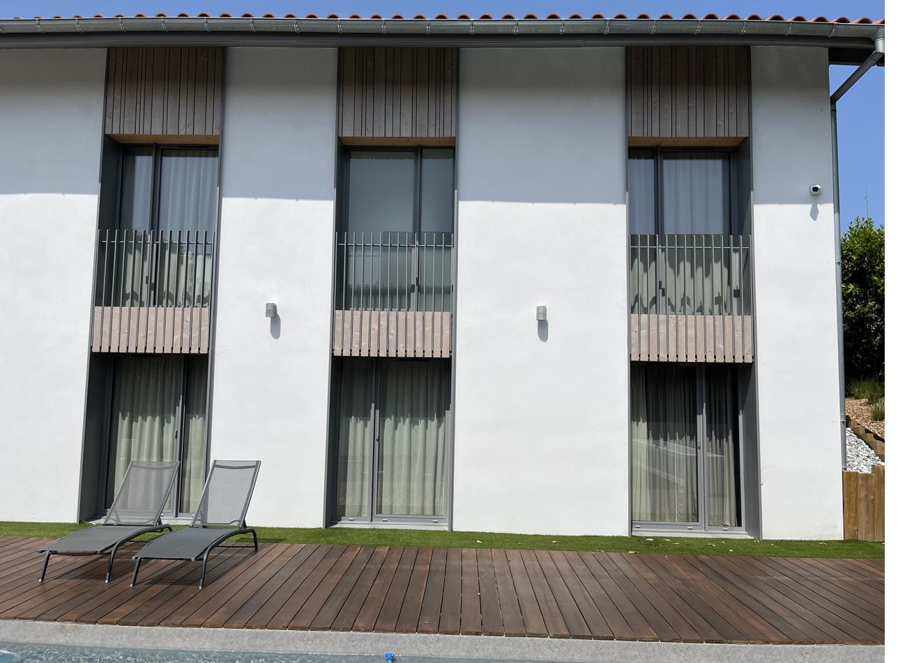 Terrasse bois au bord de la piscine, façade épurée — chantier Brisson Construction Bois